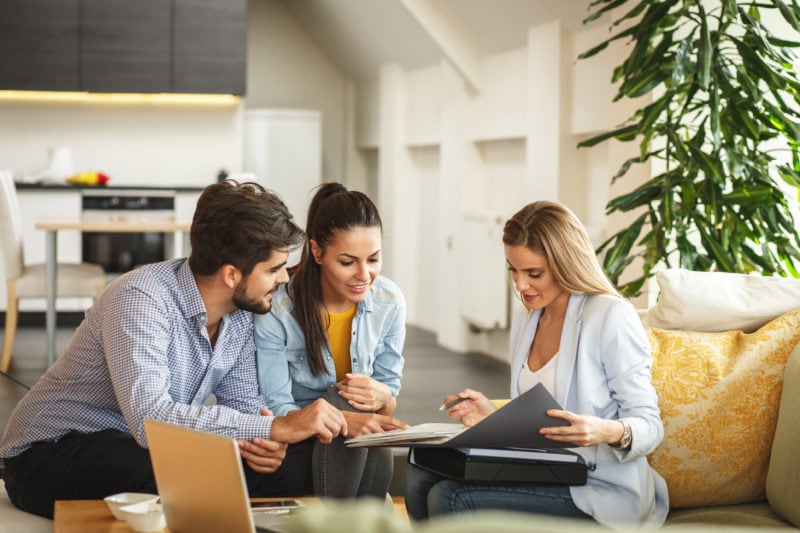 Female loan officer helping young couple with their mortgage documents